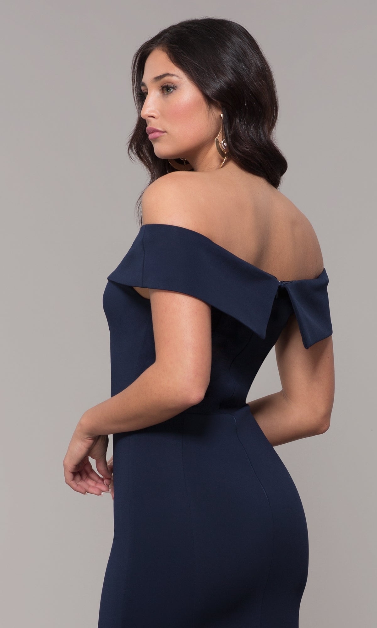 Woman wearing the Classic Off-the-Shoulder Formal Prom Dress 8258 in fitted navy blue jersey, standing sideways and looking forward against a plain background.